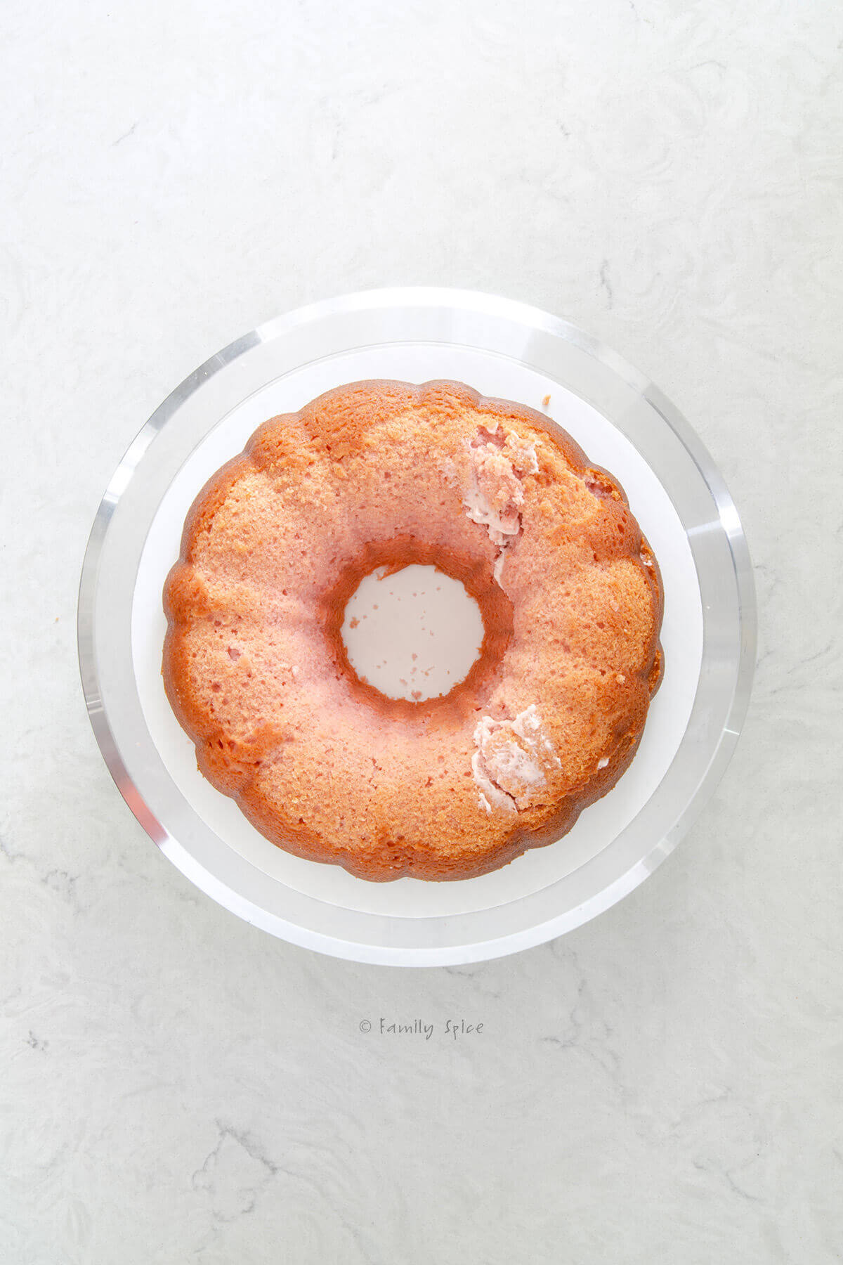 Top view of a pink strawberry bundt cake on a metal cake stand