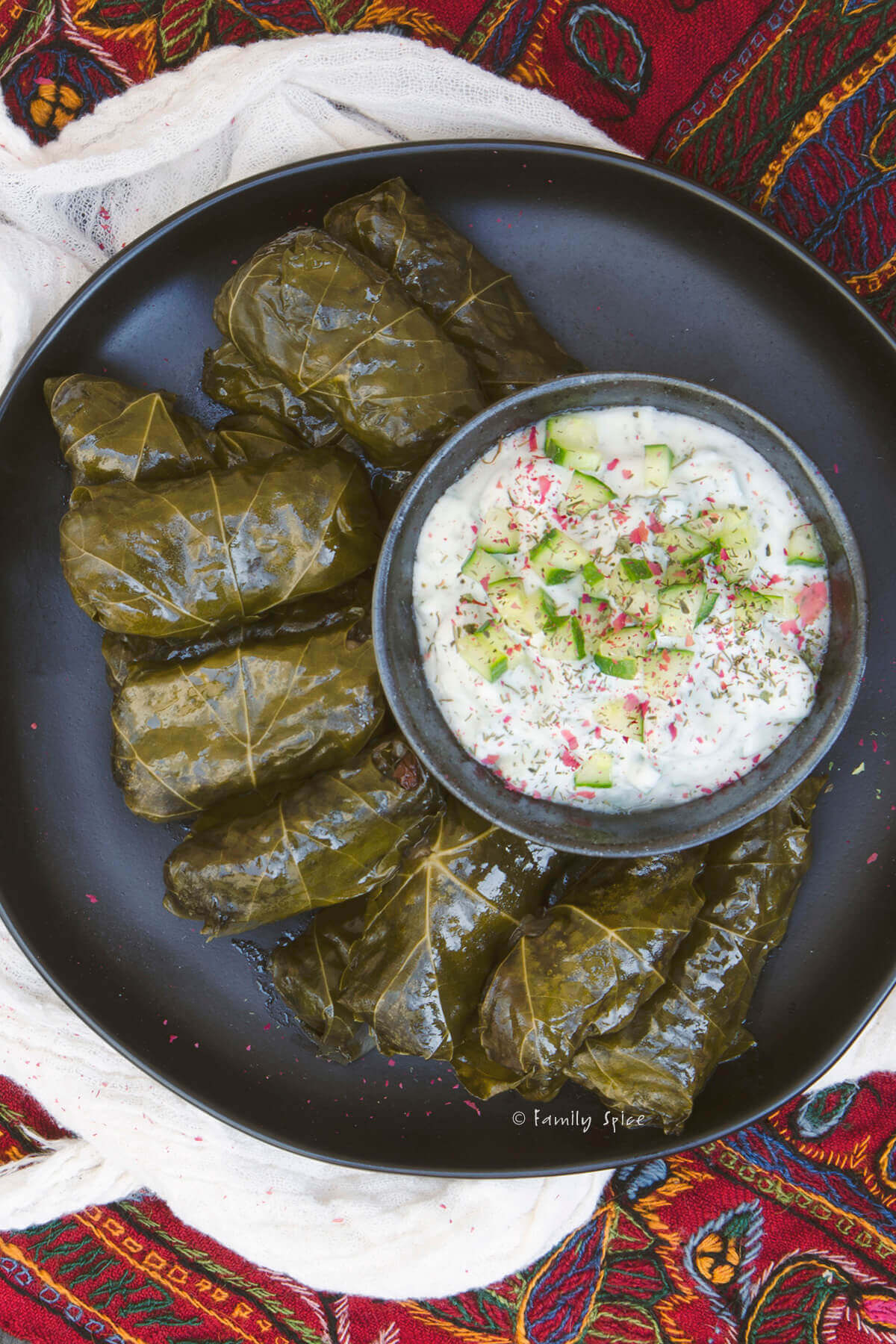 Closeup of a top view of a plate of dolmeh with a bowl of mast o khiar next to it