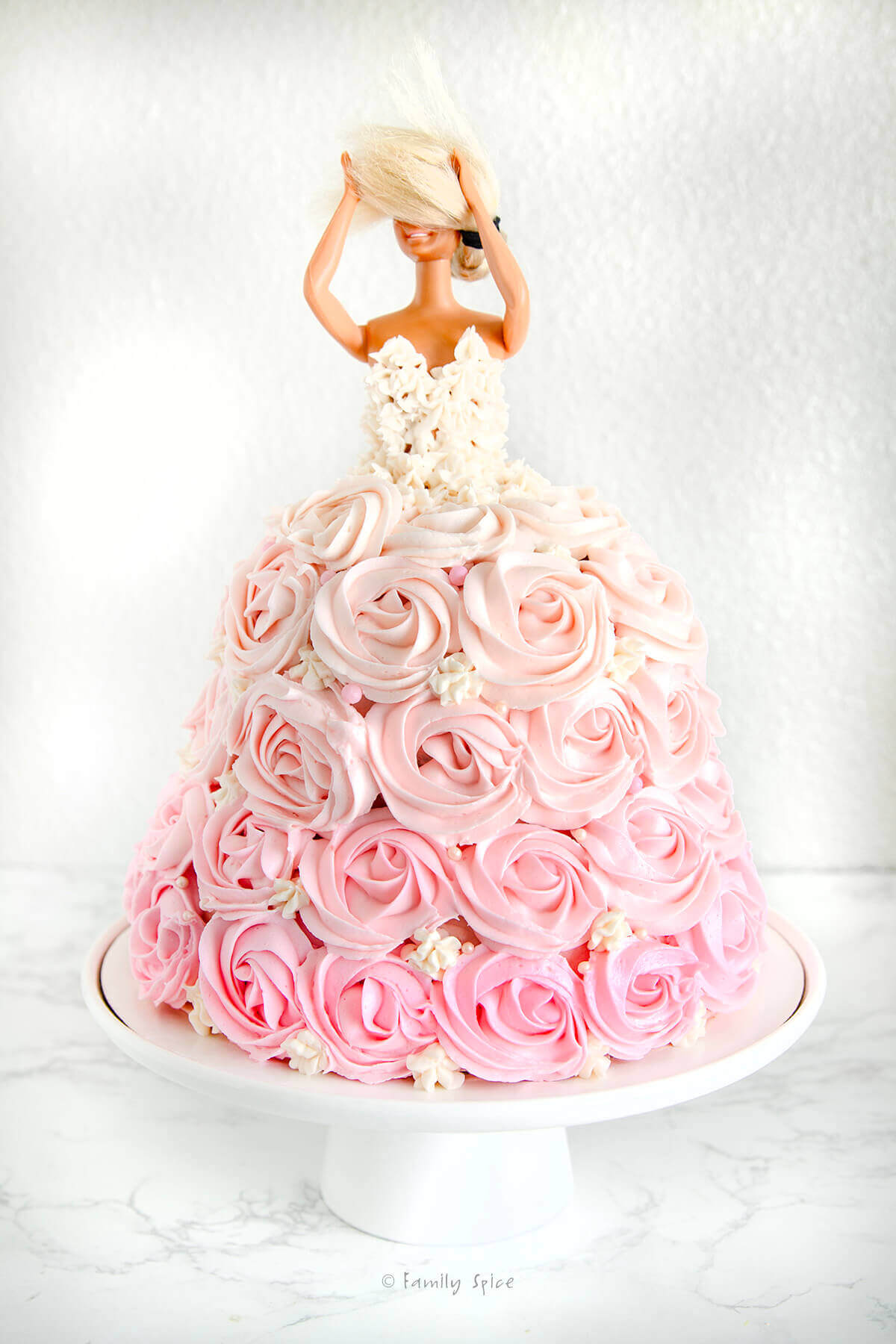 White stars piped onto a barbie in a barbie themed cake with pink ombre rosettes