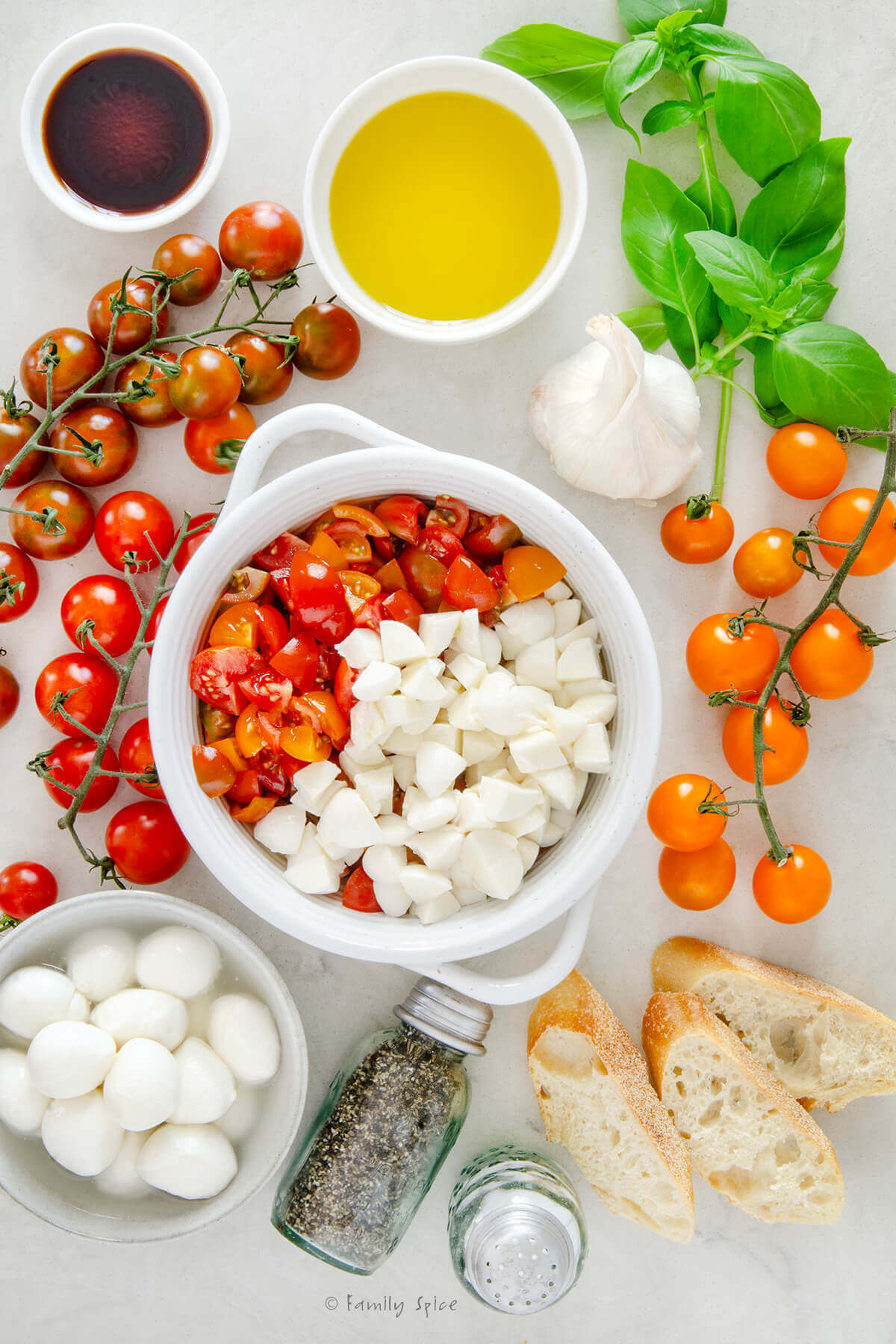 Top view of a bowl with chopped tomatoes and mozzarella in it and fresh ingredients around it