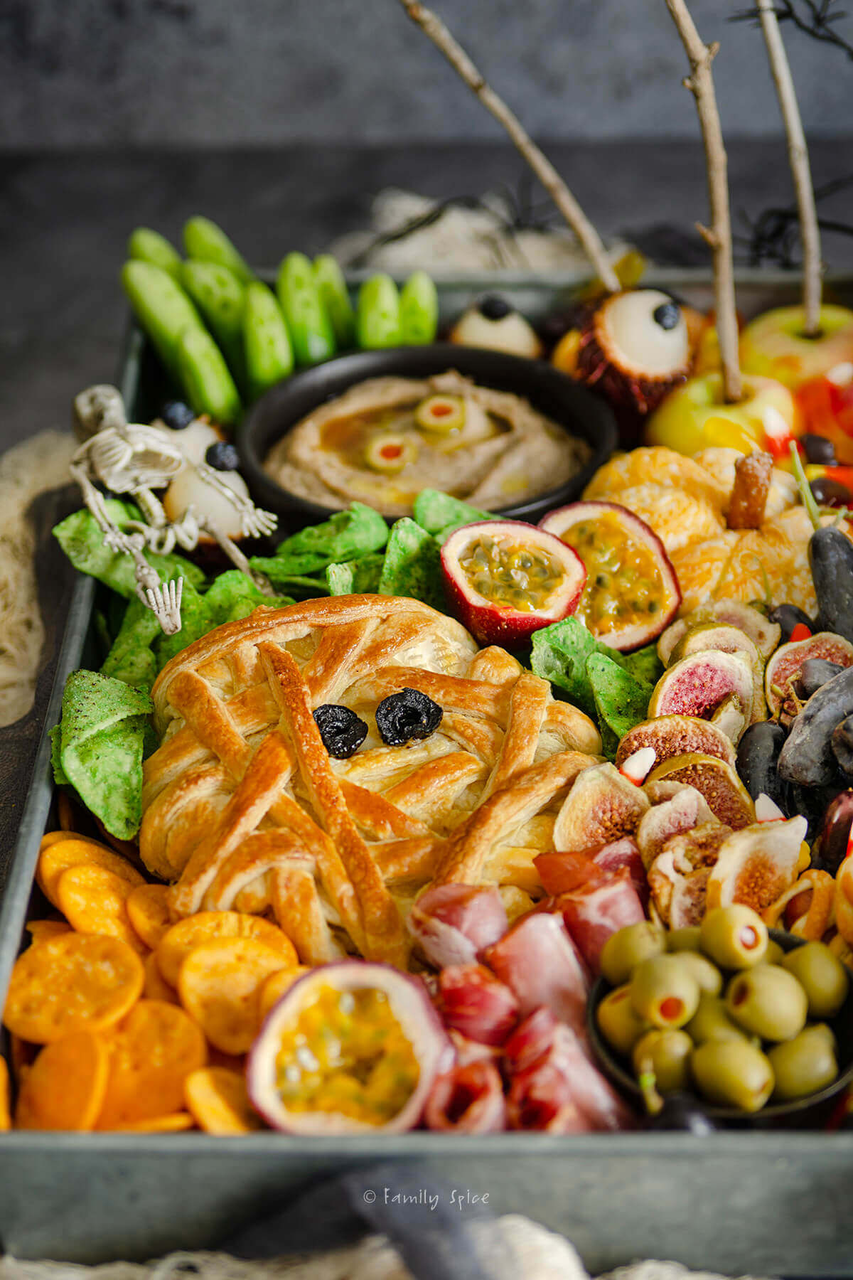 Closeup of a mummy baked brie surrounded by other items on a halloween charcuterie board
