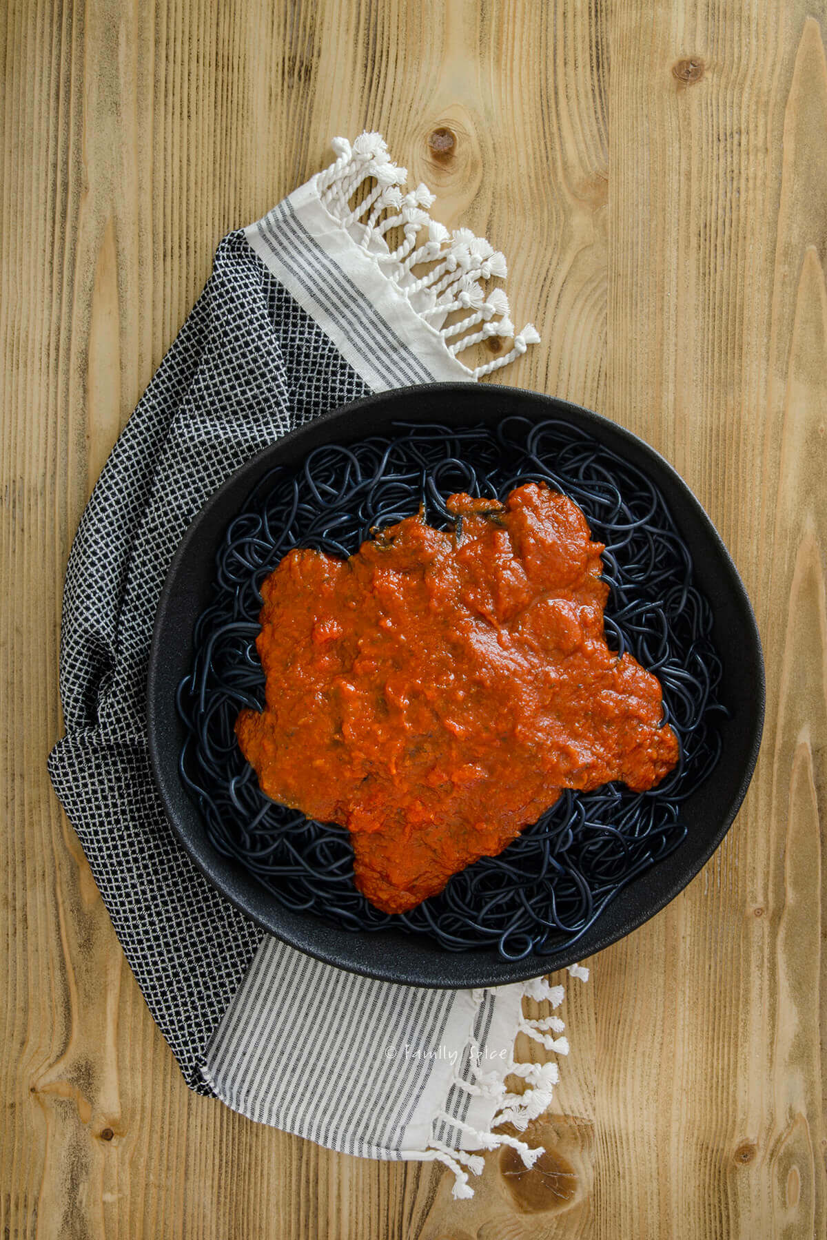 Top view of a black serving bowl with halloween pasta, black spaghetti and marinara