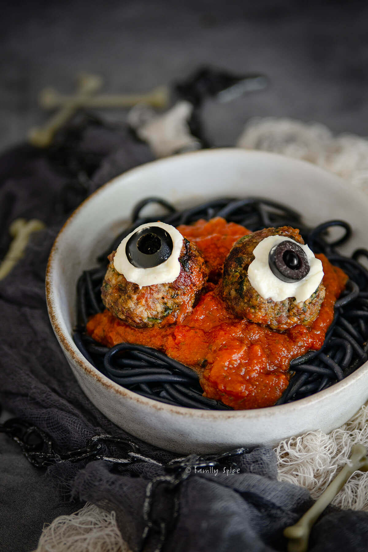 Closeup of a small bowl with halloween pasta, black spaghetti, marinara and eyeball meatball