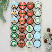 Top view of 8 different types of Christmas oreos: snowman, santa belt, reindeer, wreath, snowflake, christmas tree, gingerbread and another christmas wreath.