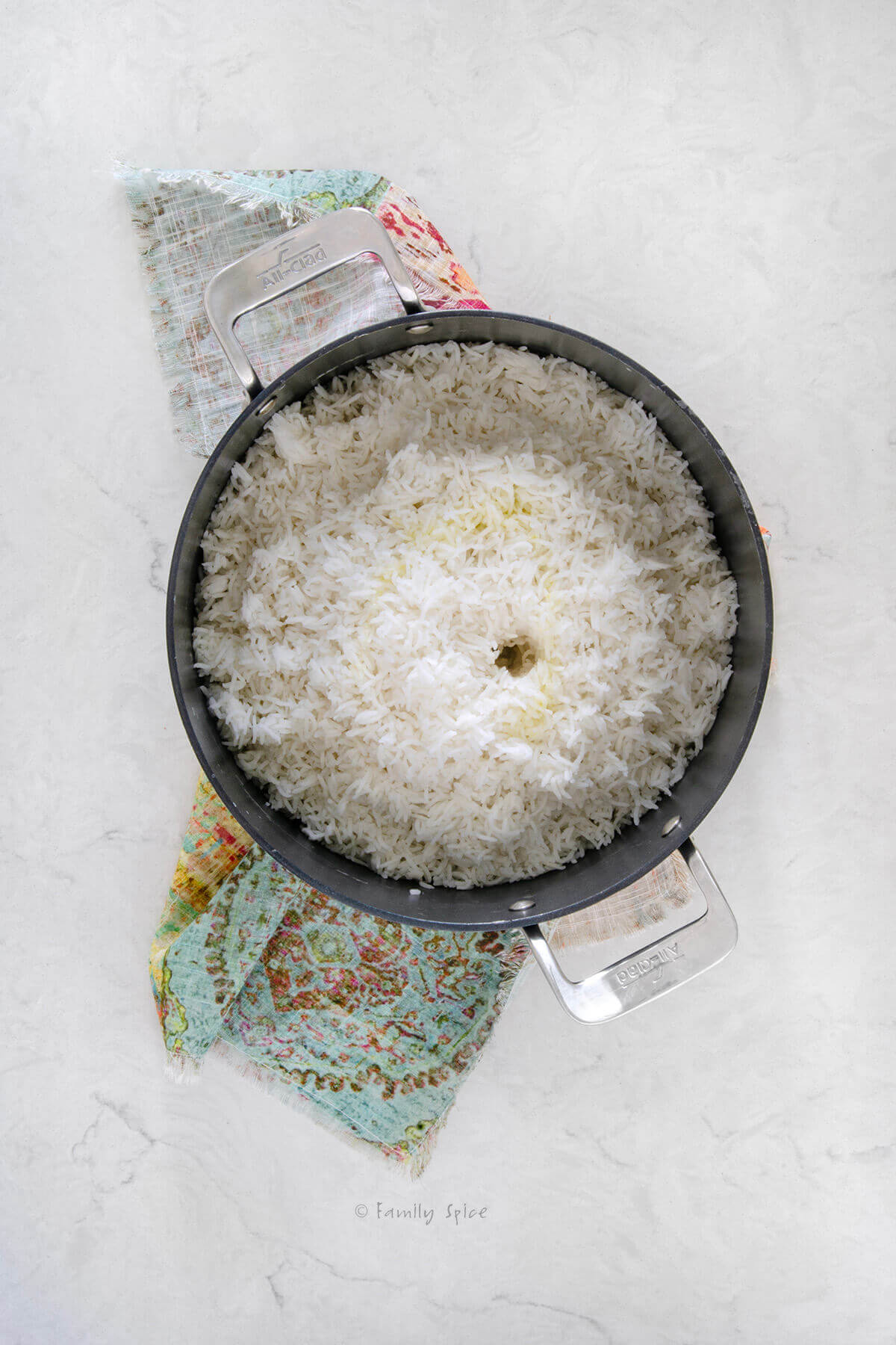 Top view of a non-stick pot with parboiled Persian rice layered in it with the center hollowed out