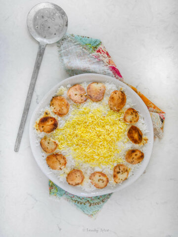 Top view of a round platter with Persian rice topped with saffron rice with potato tahdig around it