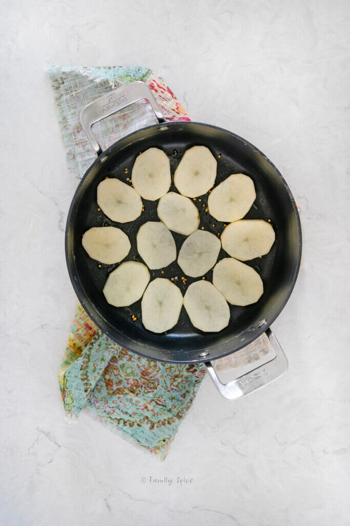 Top view of a non-stick pot lined with a layer of sliced potato on the bottom