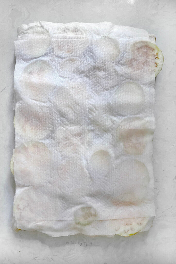Salted eggplant slices covered with paper towels waiting for the water to be released