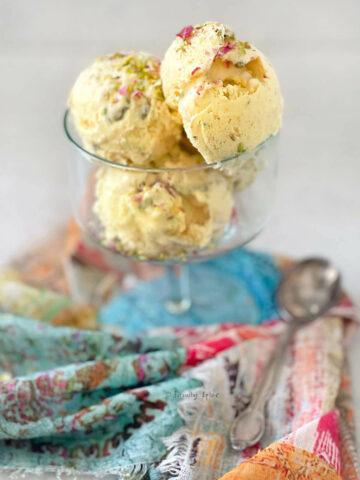 Side view of several scoops of Persian saffron ice cream (bastani) in a glass bowl