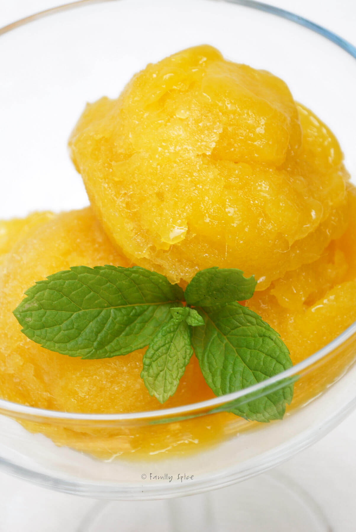 Closeup of a glass with mango sorbet and a bit of fresh mint in it