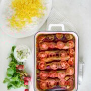 A rectangular pan with baked Perisan eggplant stew (khoresh bademjoon) a platter of Persian rice, a bowl of mast o khiar and fresh radishes