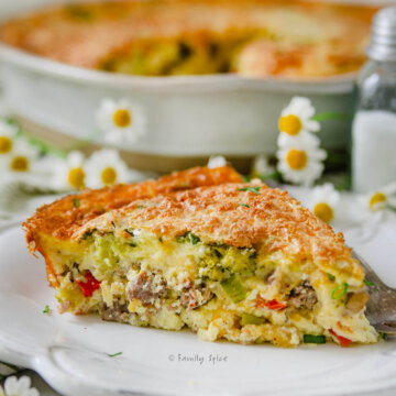 Close up of a slice of cottage cheese quiche on a white plate with the rest of the quiche in a pie dish behind it.