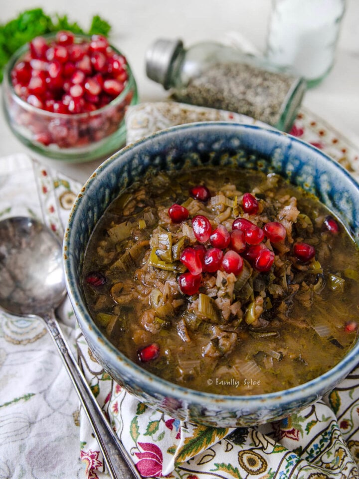 Closeup of a bowl of ash anar, Persian pomegranate soup on a colorful napkin.