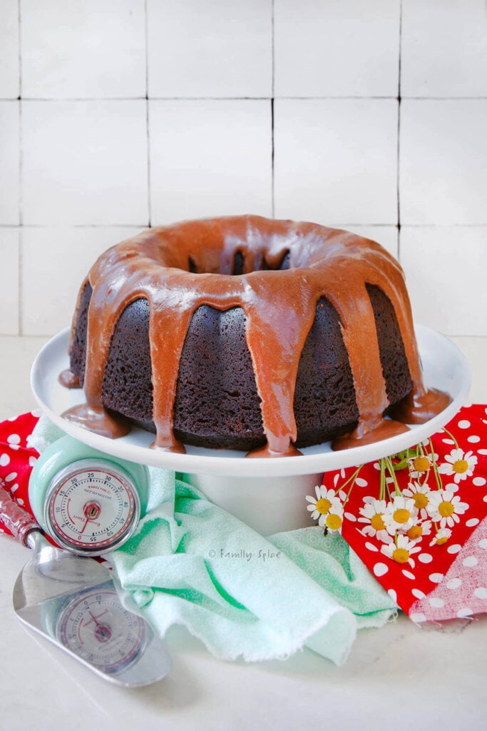 Side view of a glazed root beer cake on a white stand with red and light blue napkins.