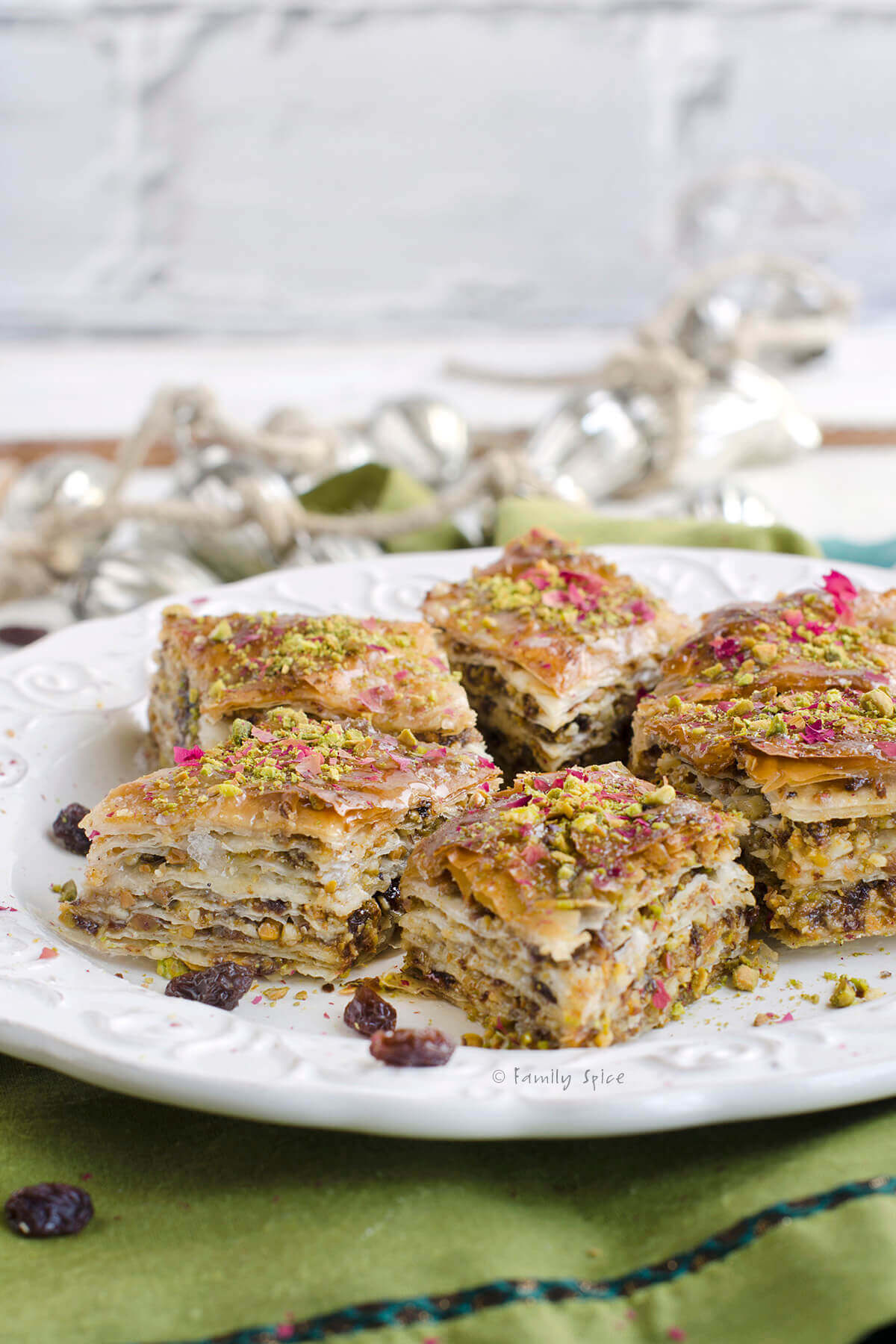 Side view of pieces of Persian baklava on a white plate and green napkin.