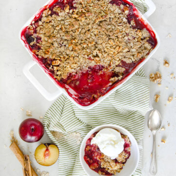 A freshly baked plum crisp with a small bowl with a single serving in it topped with vanilla ice cream.