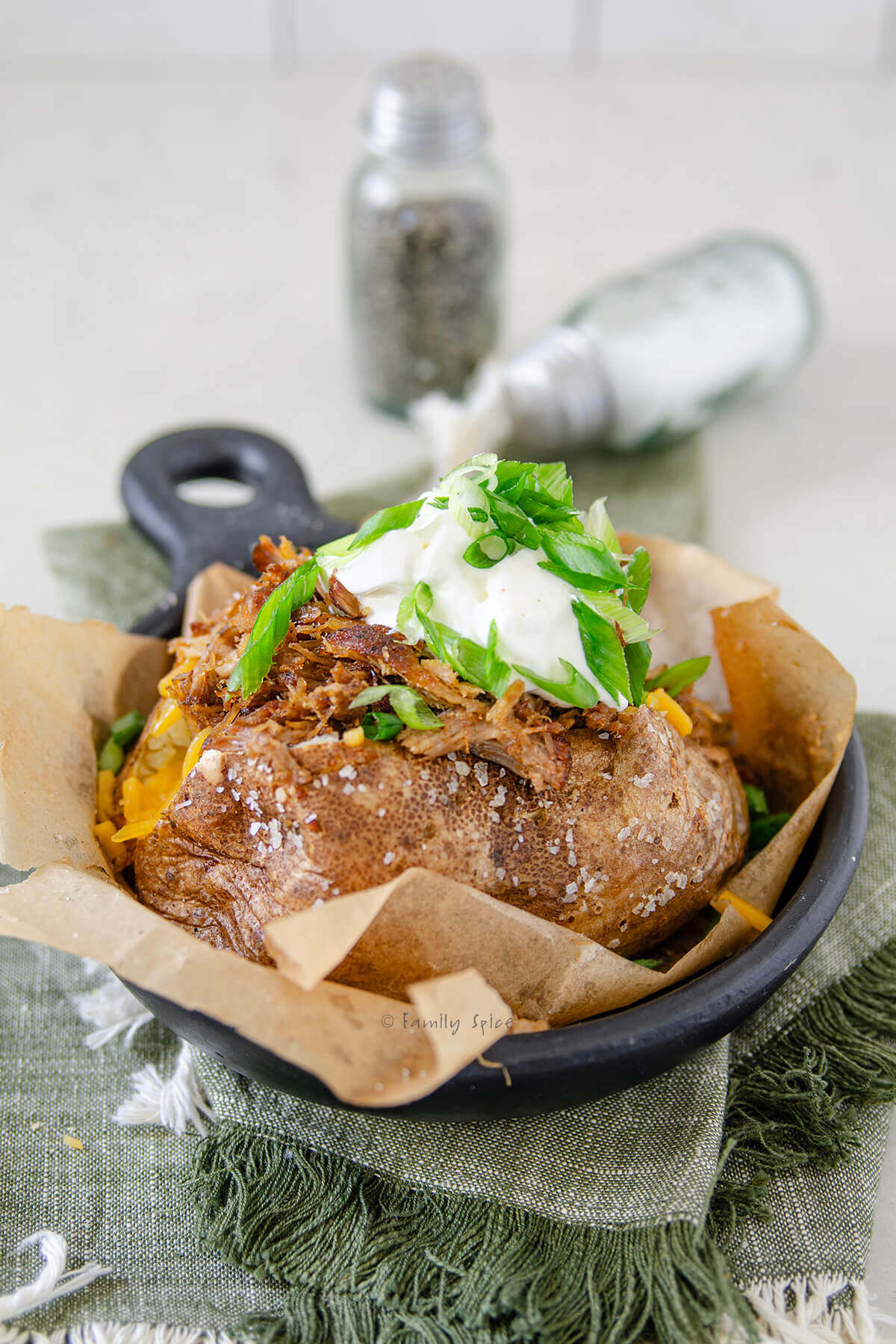 Side view of a fully loaded pulled pork baked potato.
