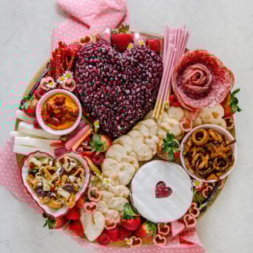 A valentine charcuterie board on a round wooden tray.