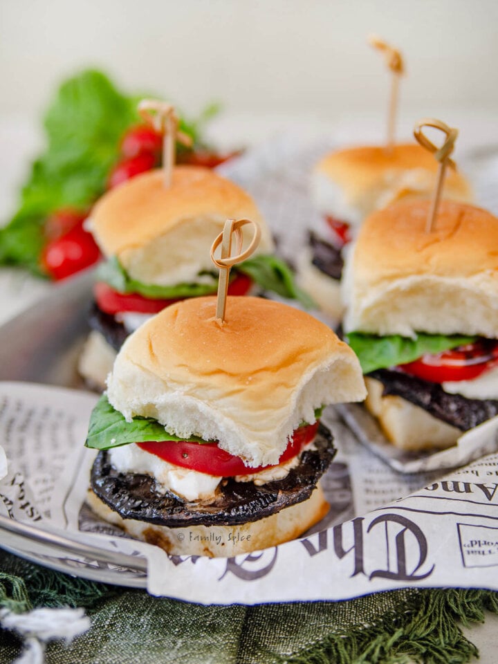 Several mushroom sliders on a tray with newspaper parchment paper.