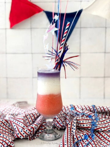 A festive glass with a layered drink showing a red, white and blue cocktail.