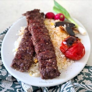 Closeup of a plate with oven baked koobideh kabob on basmati rice.